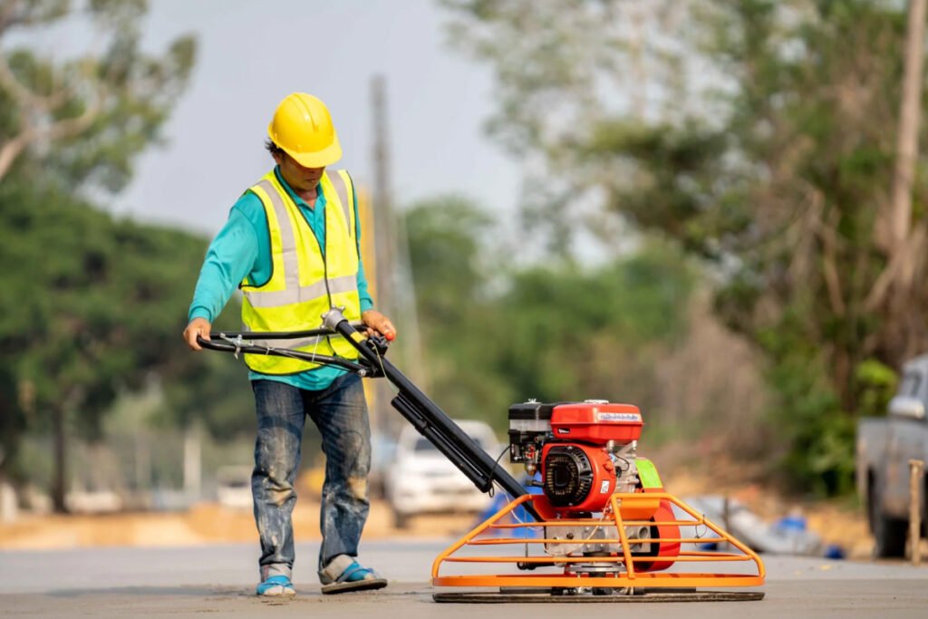 Minor civil worker pouring water on road construction project