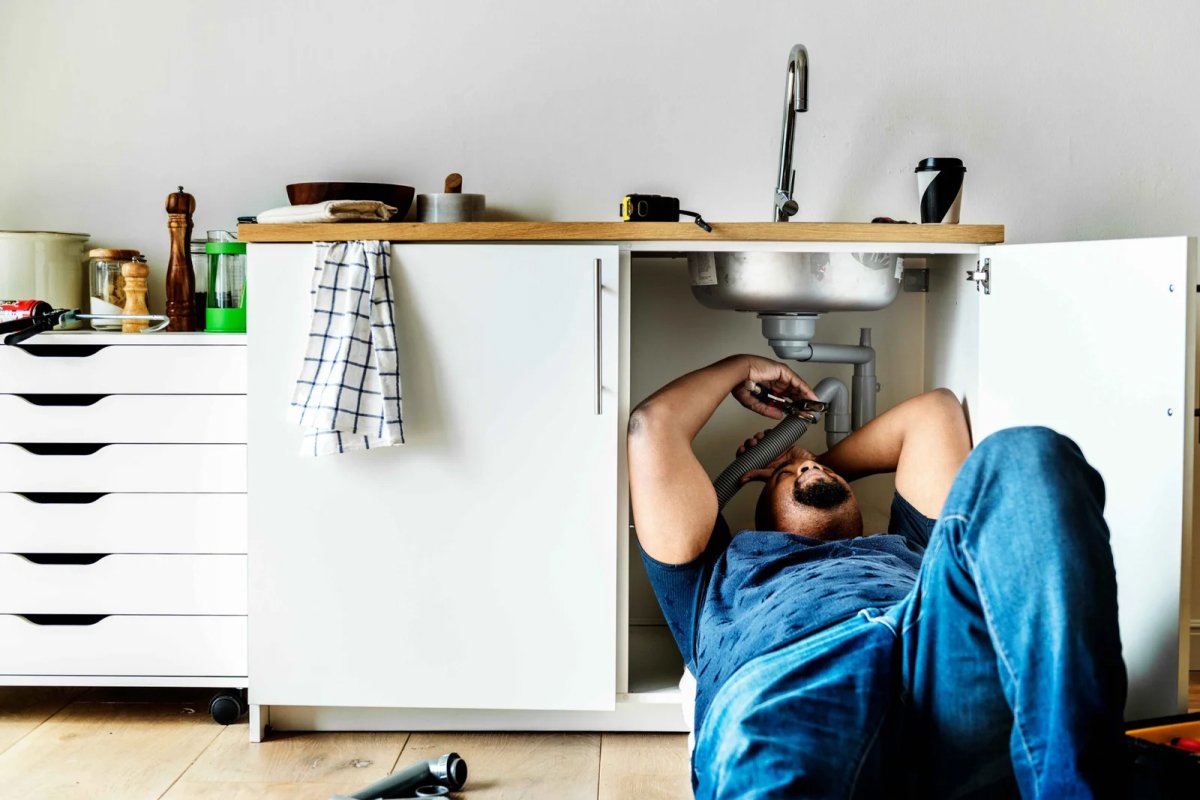 Man fixing plumbing under a sink